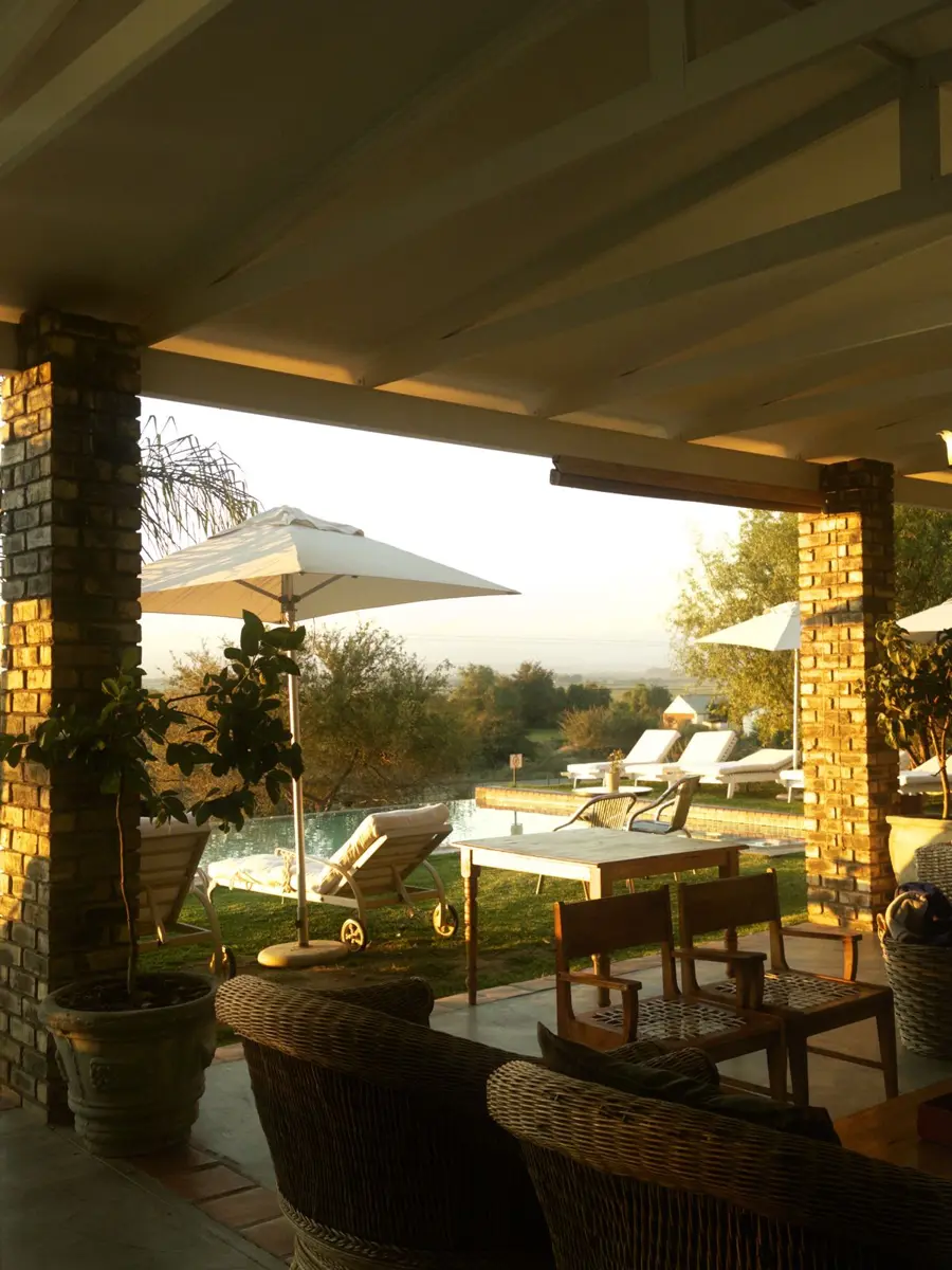 A shaded terrace looking out over a pool and garden