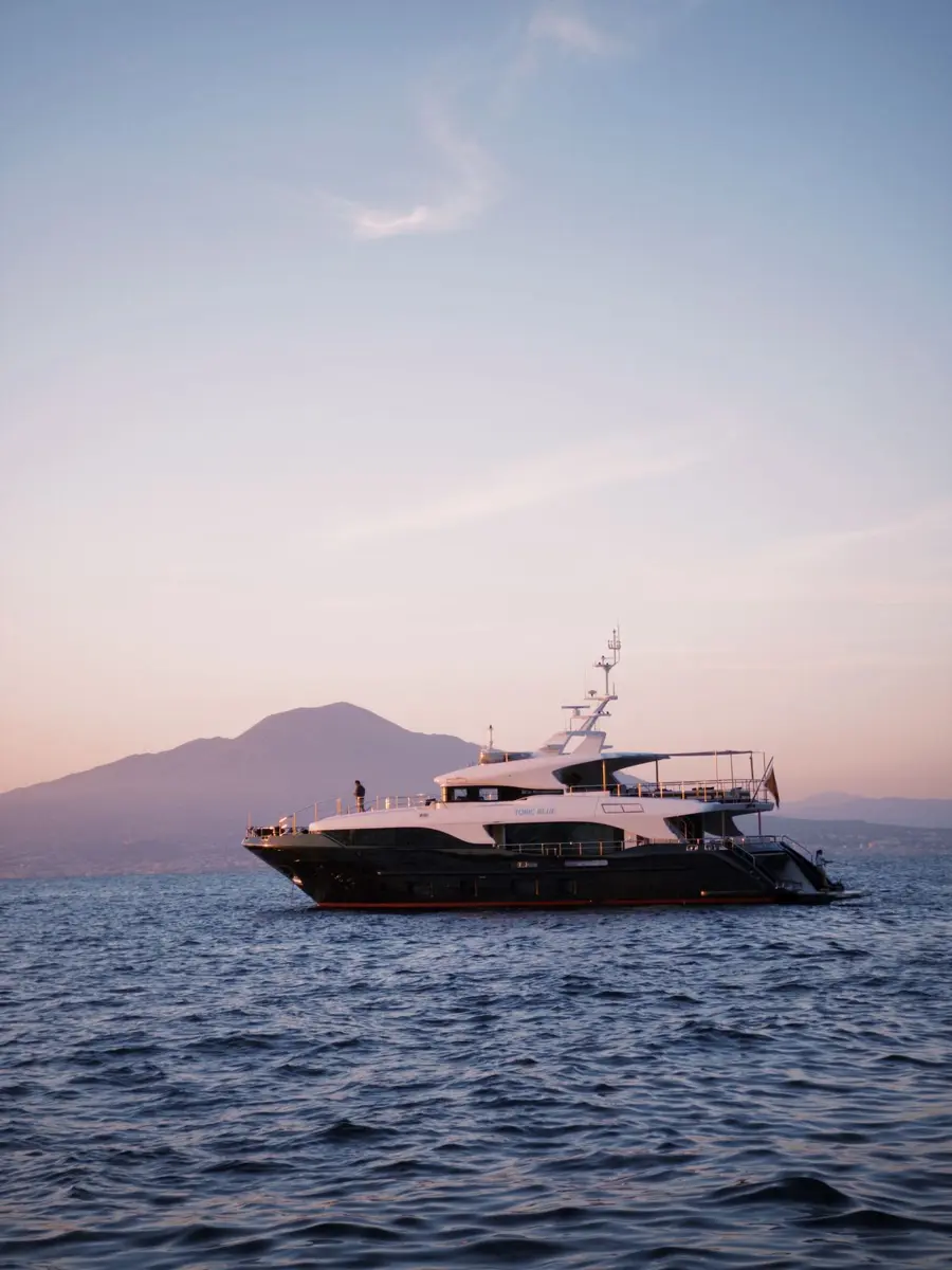 A white yacht on the sea with a mountain silhouette at dusk