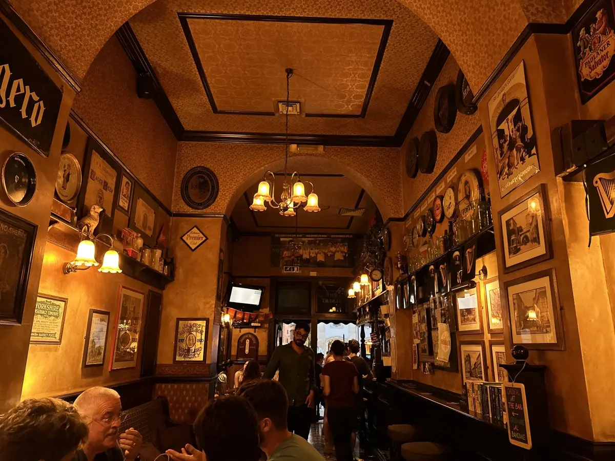 A crowded, wood-panelled pub lit by warm lamps
