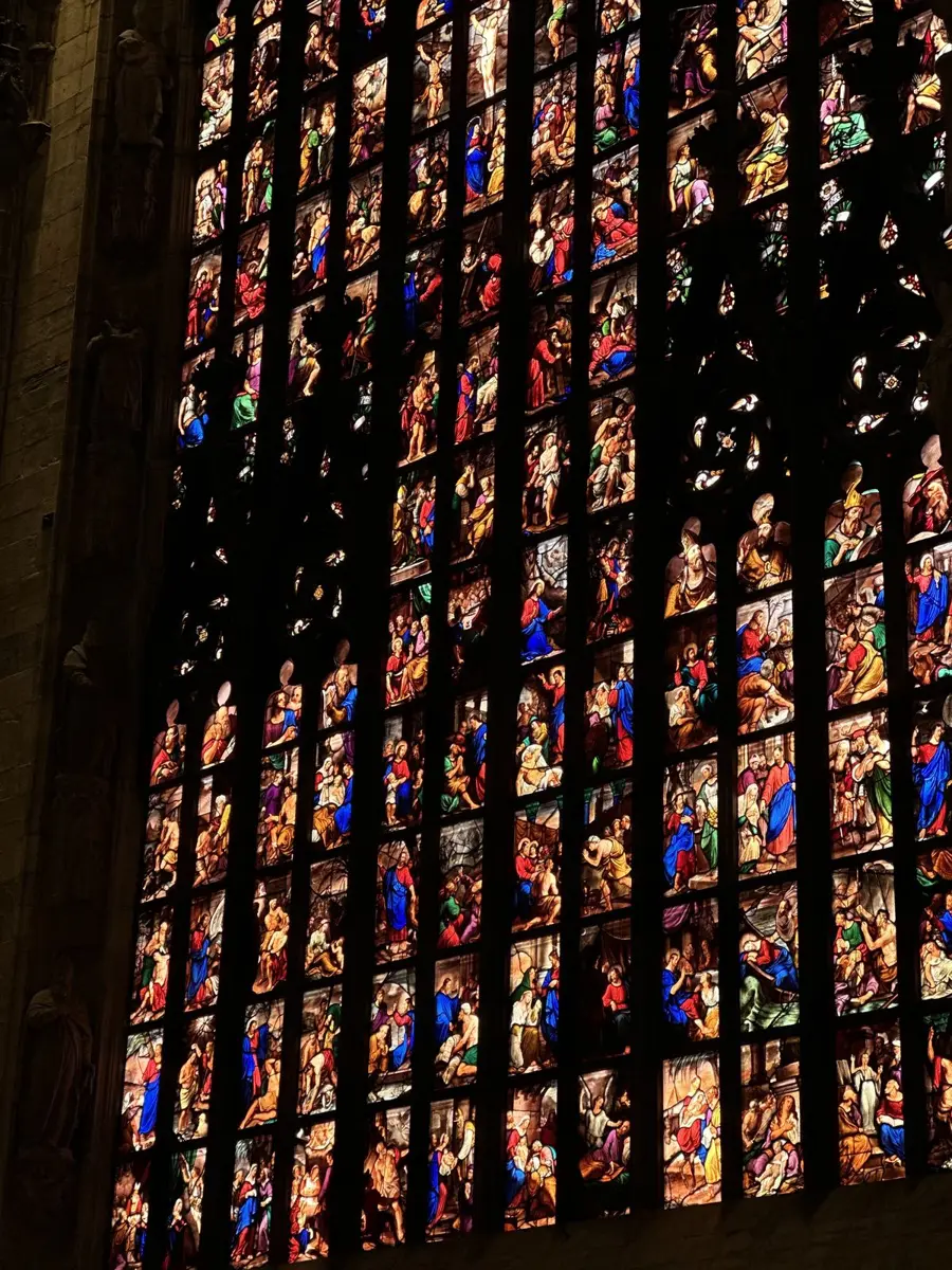 Floor-to-ceiling stained glass windows glowing in a dark cathedral